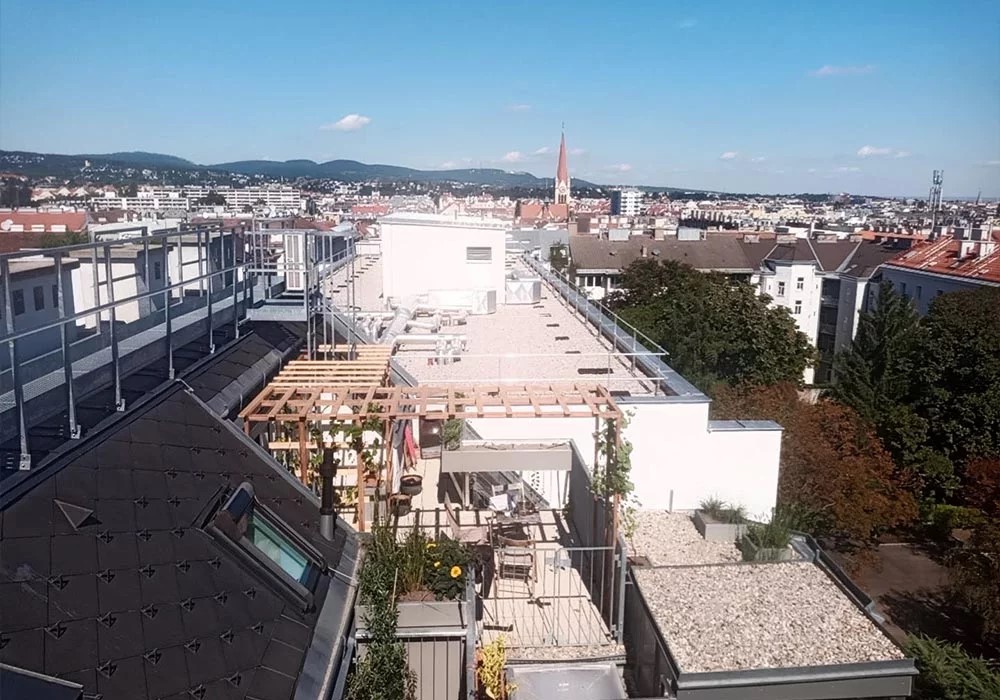 Schöner Blick über die Dächer von Wien. Fotografiert mit einer Drohne in Ottakring. Man sieht im Vordergrund eine kleine Dachterrasse die von Garten|Concept neu gestaltet wurde.
